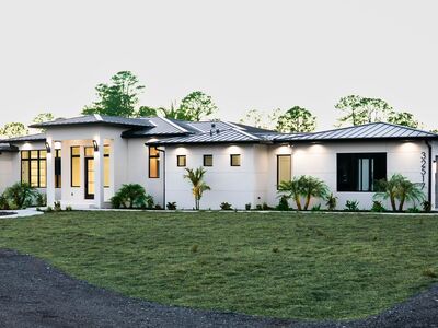 a white house with dark grey metal roof and large windows